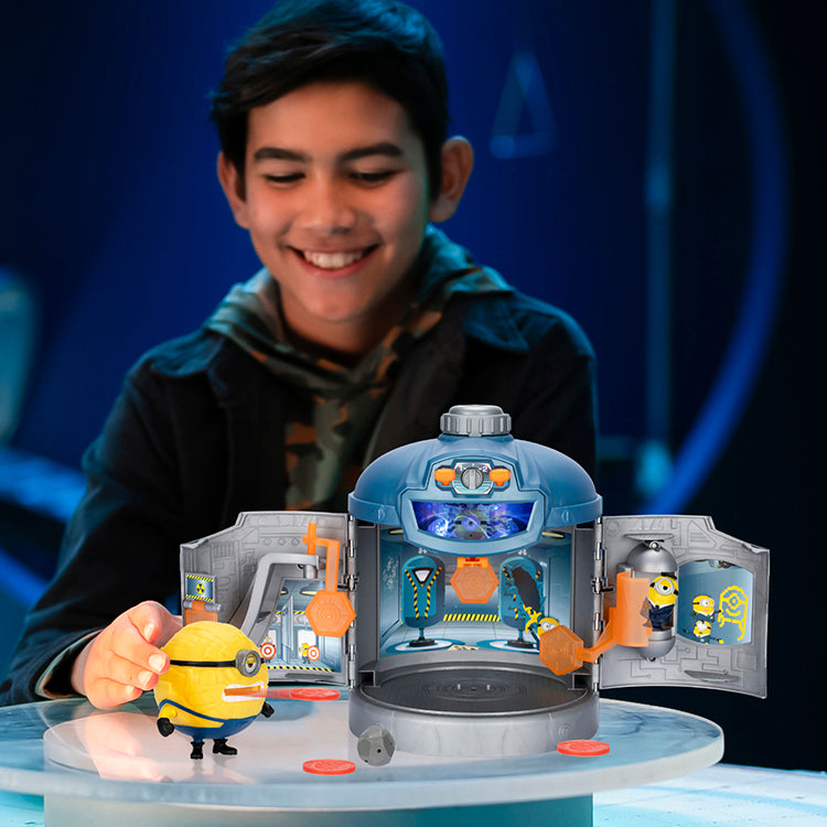 Happy child playing with Despicable Me 4 Transformation Chamber and Mega Minion toy set on a table.